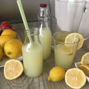 bottles of freshly home made cloudy lemonade with lots of really fresh juicy lemons
